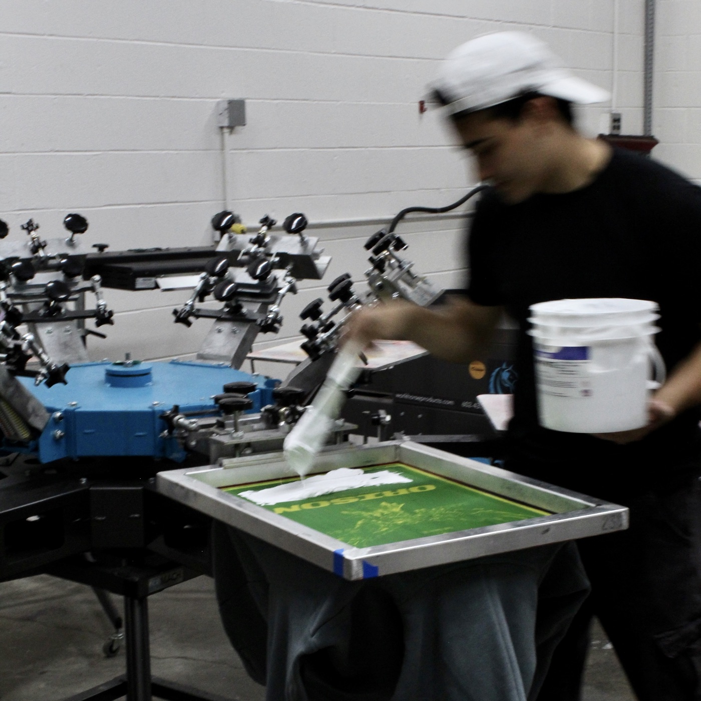 YD Print Pros at work on the press, flooding a screen with white ink